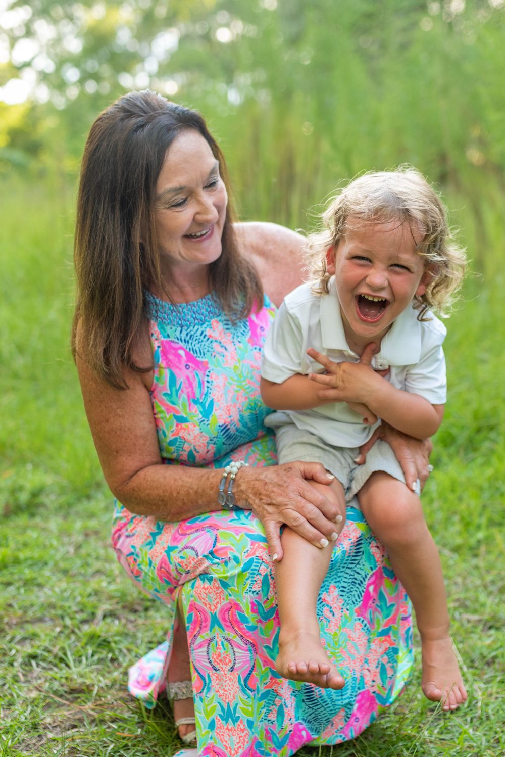 Playful moments captured between parent and child sitting in green grass.