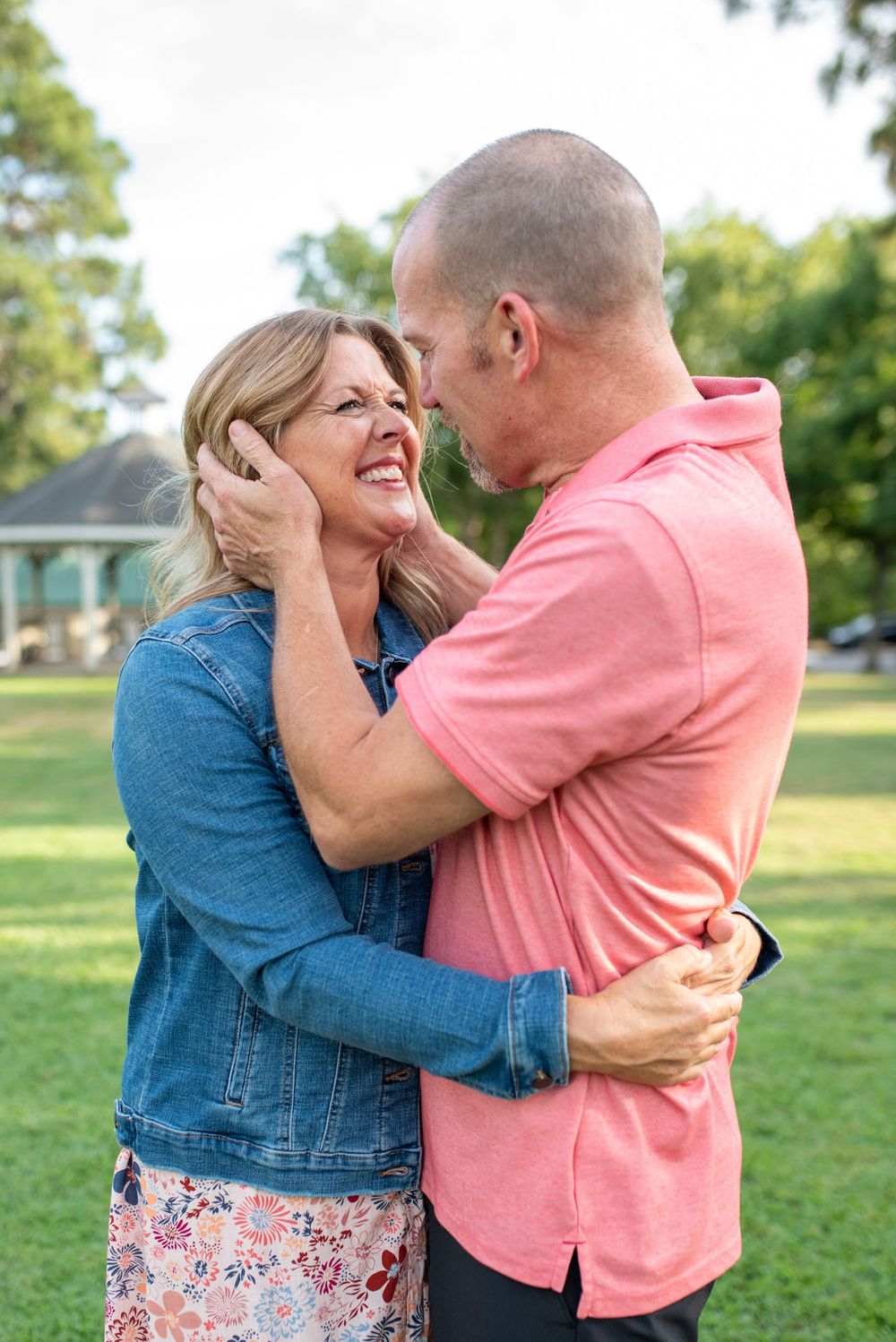 Romantic couple embracing and laughing together in a park setting.