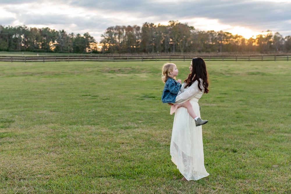 Family running and playing together in open field at sunset.