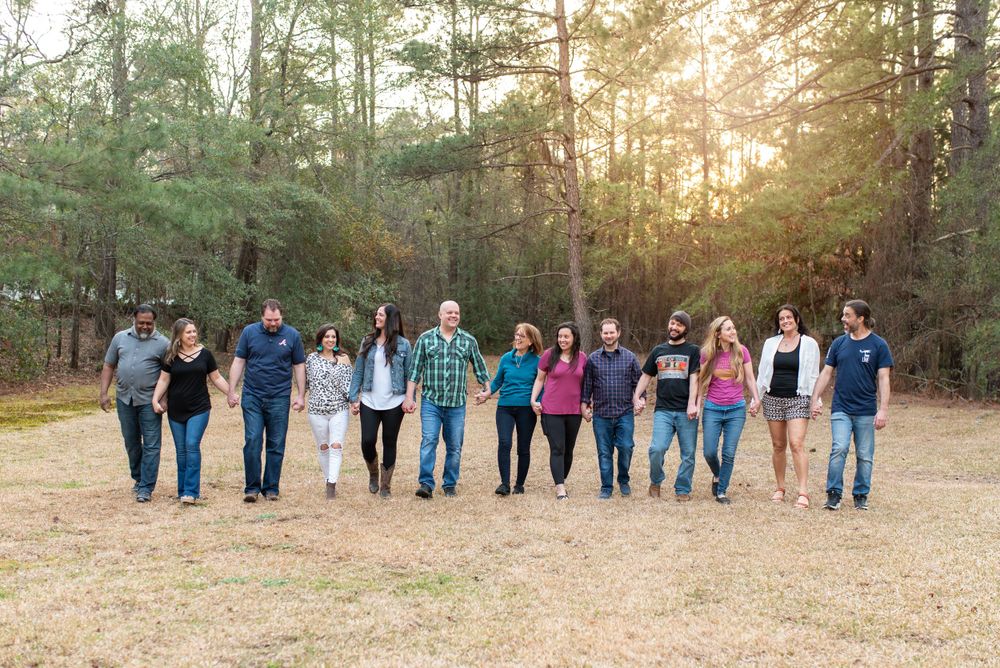 Large group walking together in line through wooded area at sunset.