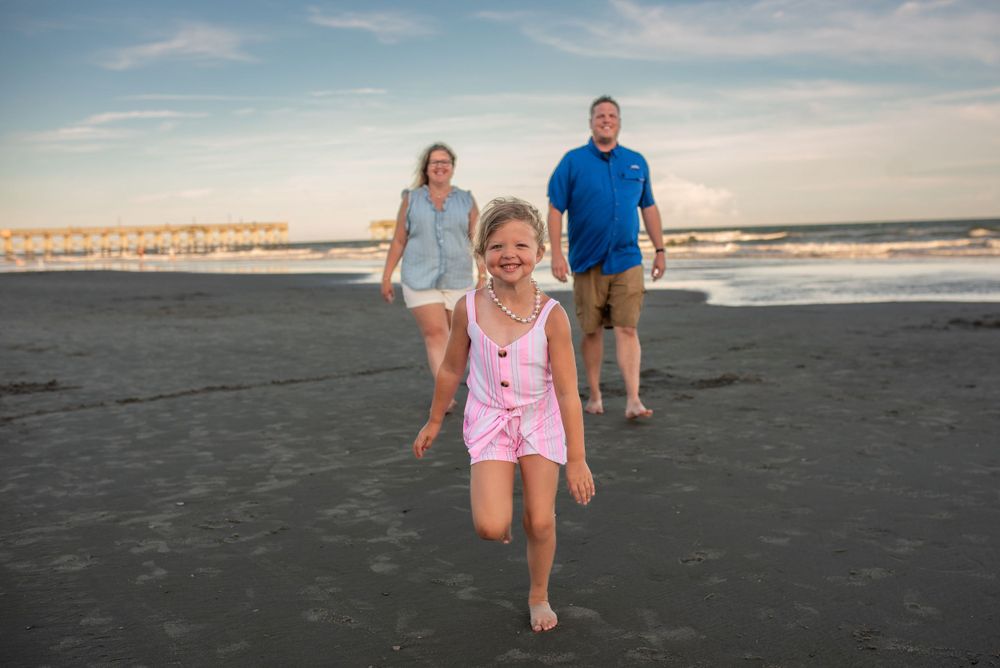 Family walking and playing together on beach at sunset.