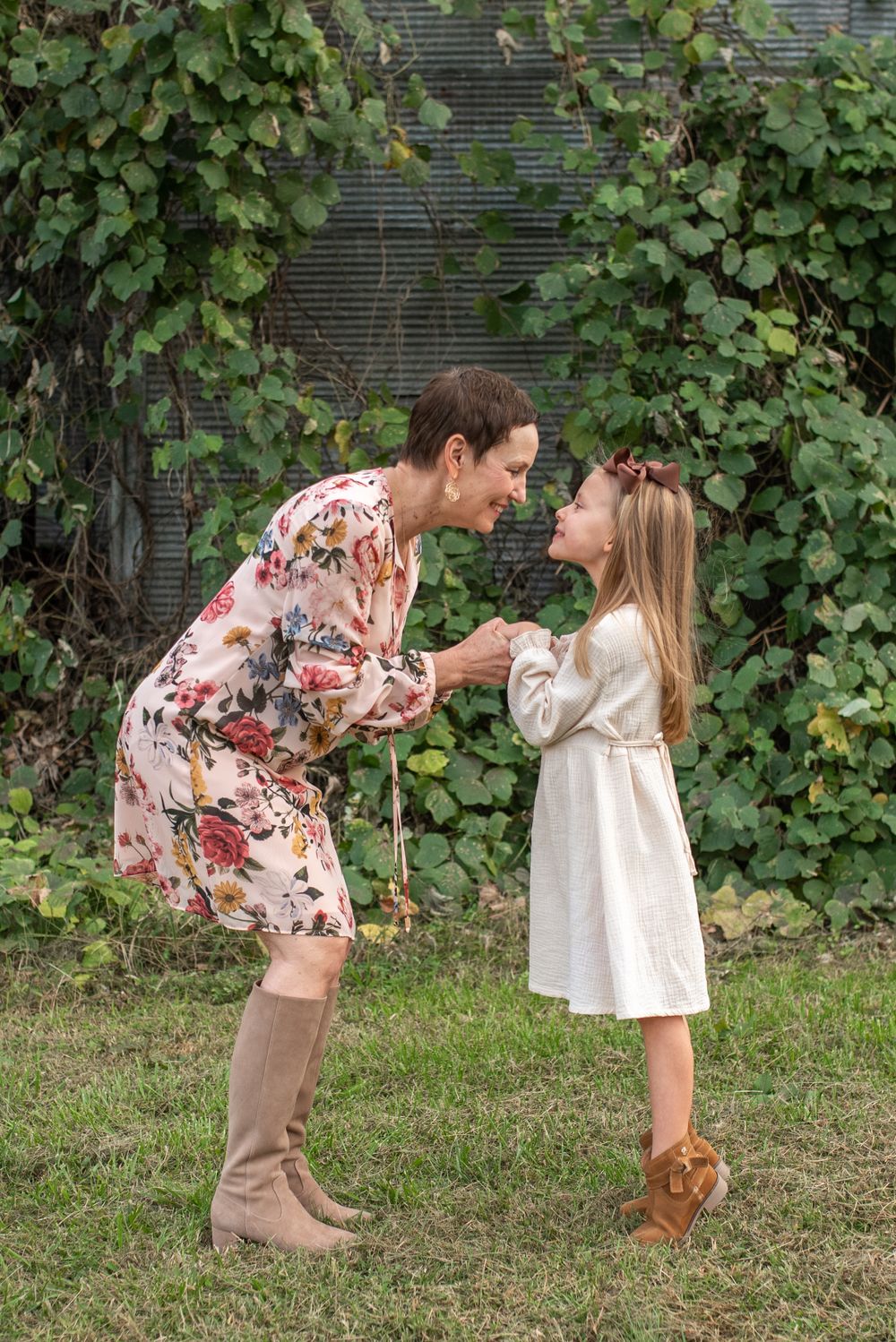 Sweet moment between parent and child in coordinated floral and white outfits outdoors.