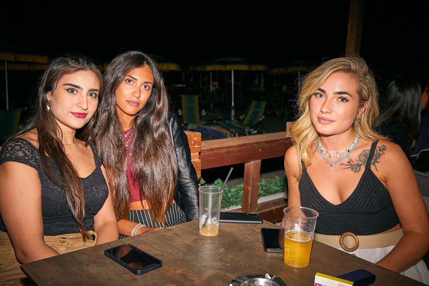 Group enjoying drinks at outdoor restaurant table.