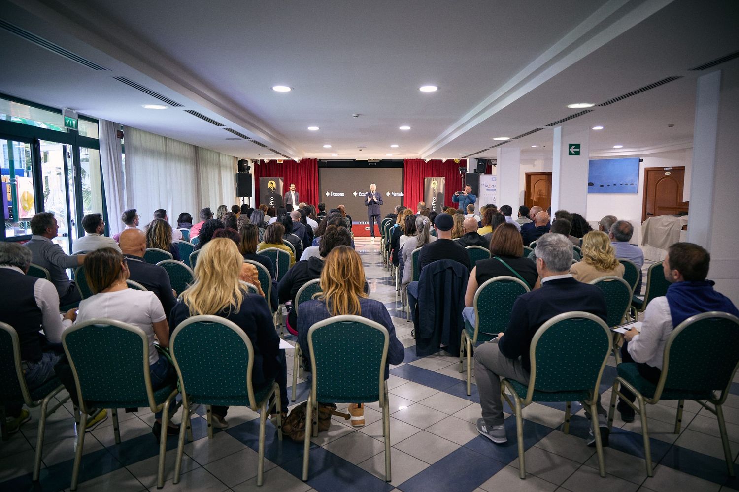 Business conference audience seated in rows of chairs in hotel meeting room.