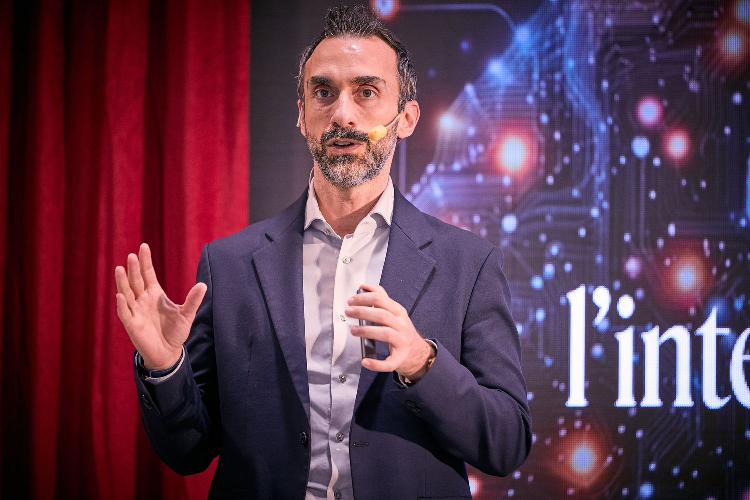 Speaker presenting on stage with digital background at professional conference.