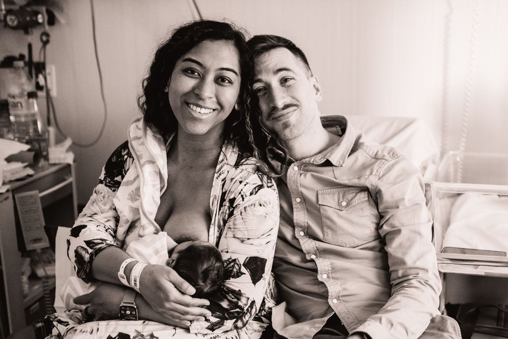 Happy couple holding their newborn baby in a hospital room.