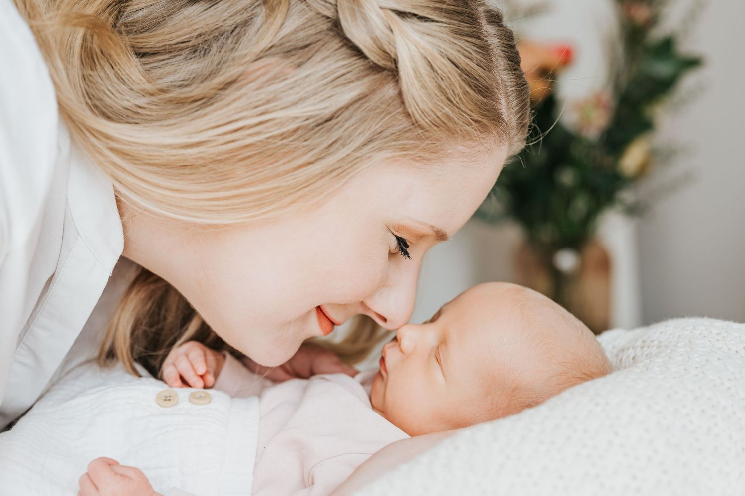 Tender moment between parent and newborn baby against white bedding.
