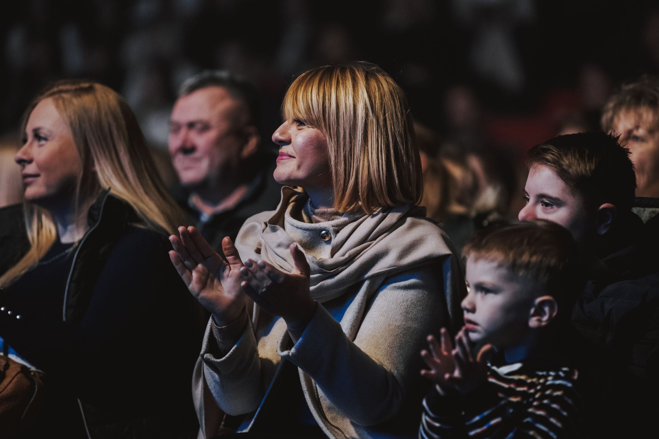 Concert audience members watching intently during an indoor performance.