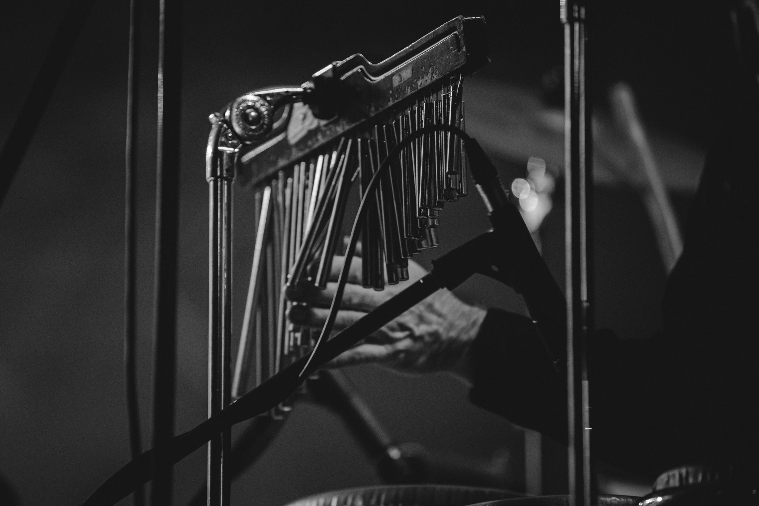 Black and white image of a wind chime instrument mounted on a stand during a concert performance.