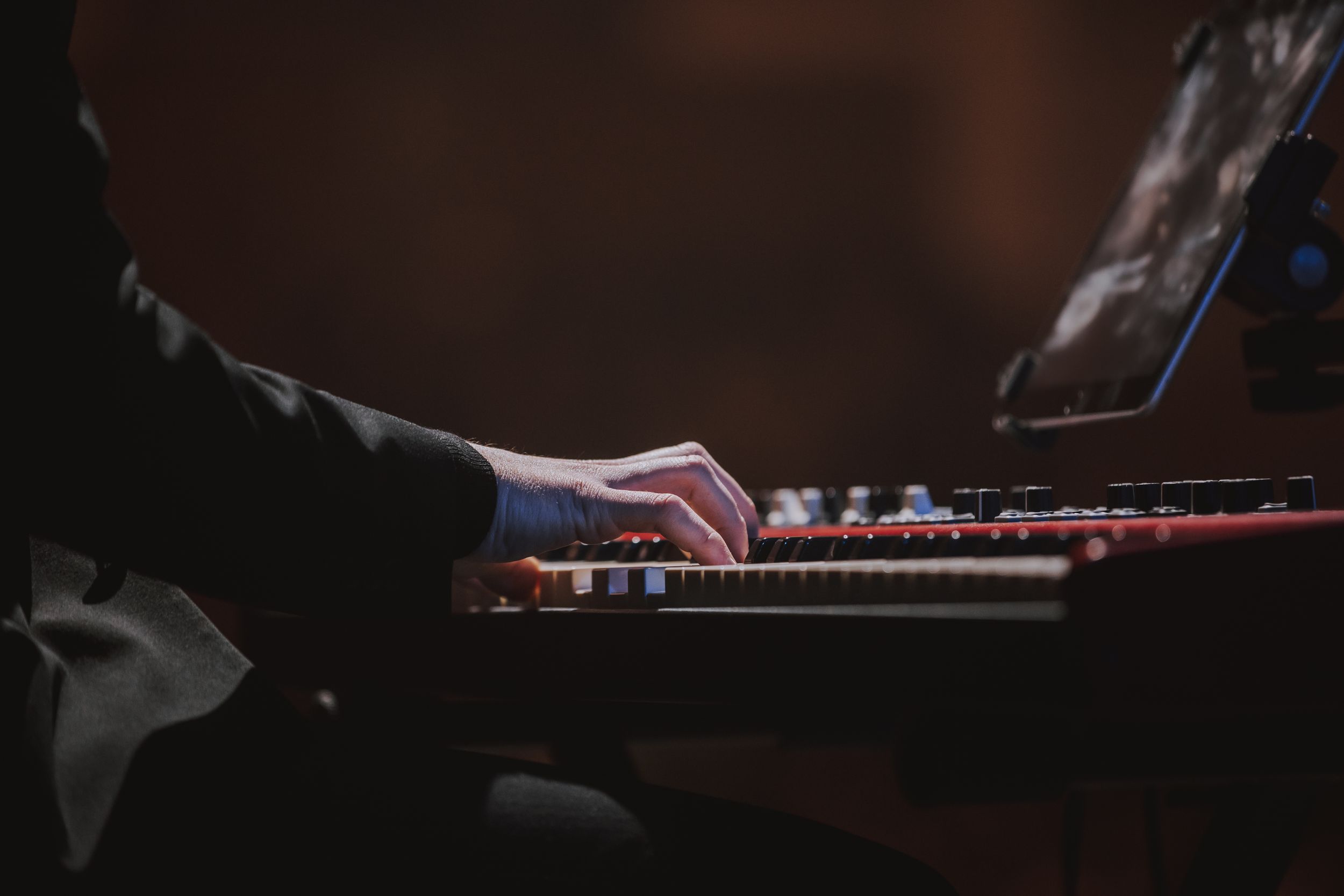 Close-up shot of hands playing piano keys in dark atmospheric lighting.