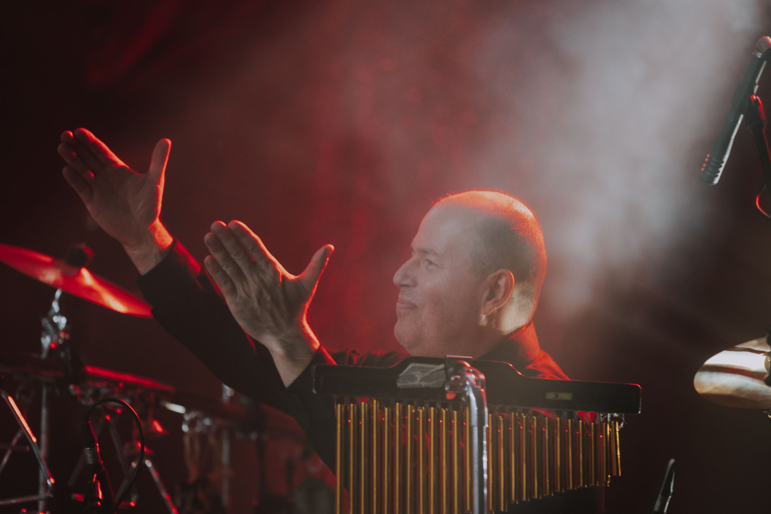 A musician performing with a xylophone on stage bathed in red concert lighting.