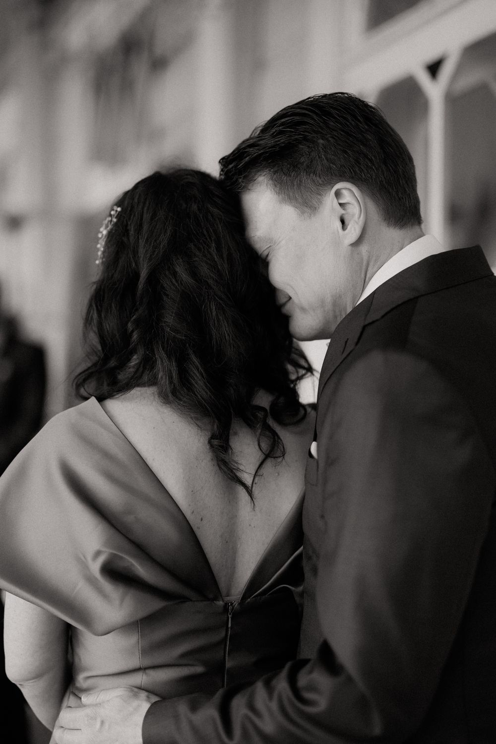 Black and white photo of a couple sharing an intimate moment, groom kissing bride on the forehead at wedding.