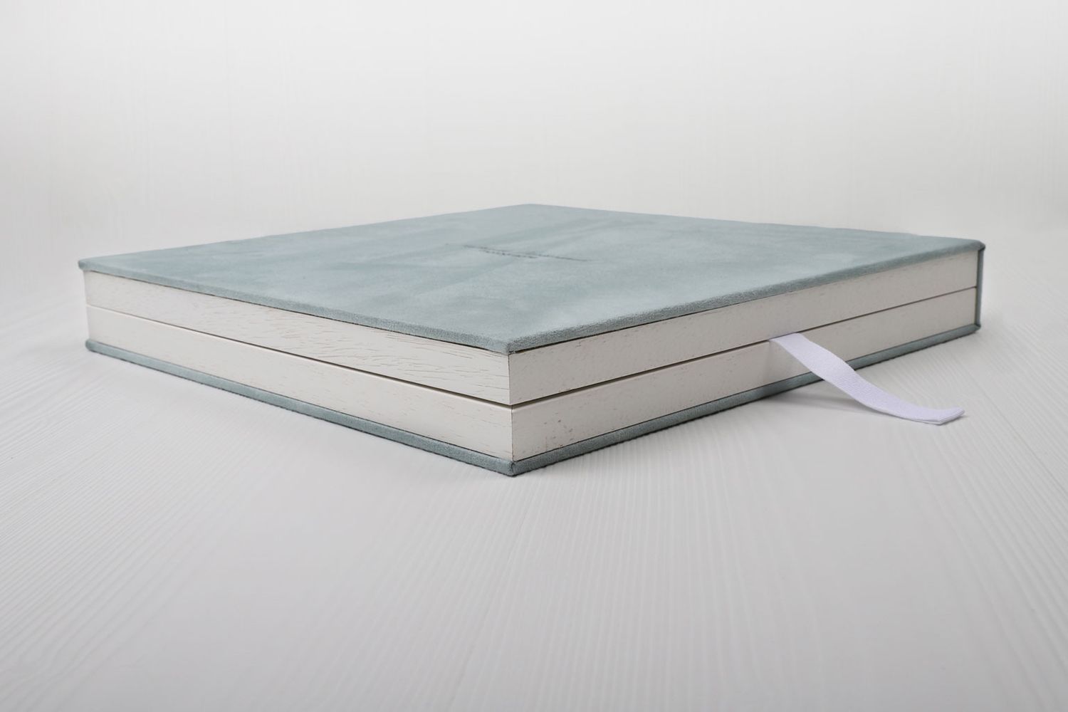 Album photo professionnel avec une couverture en daim bleu clair et un marque-page en ruban blanc.