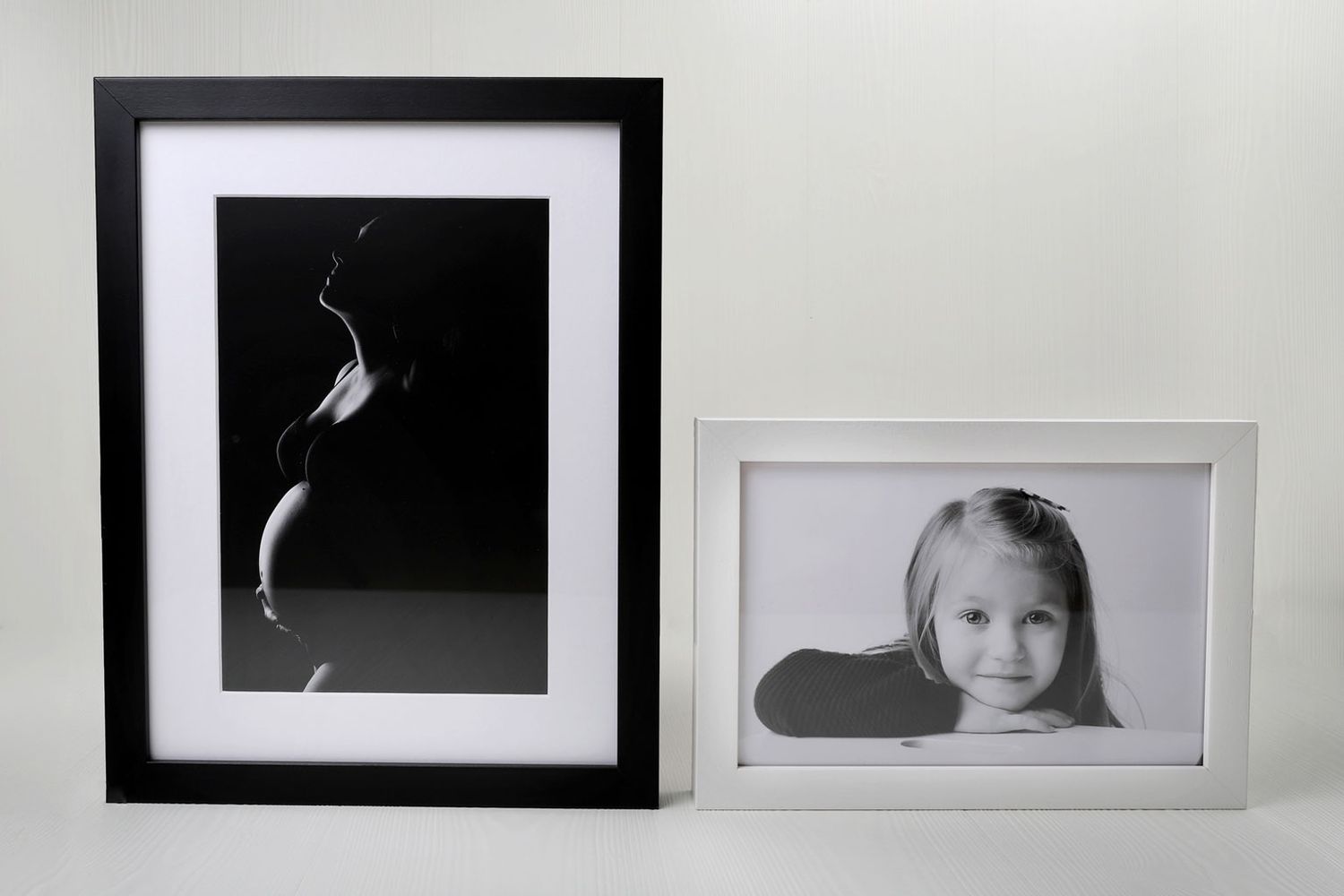 Deux photographies encadrées côte à côte, l'une en noir et blanc abstraite et l'autre un portrait dans des cadres simples.