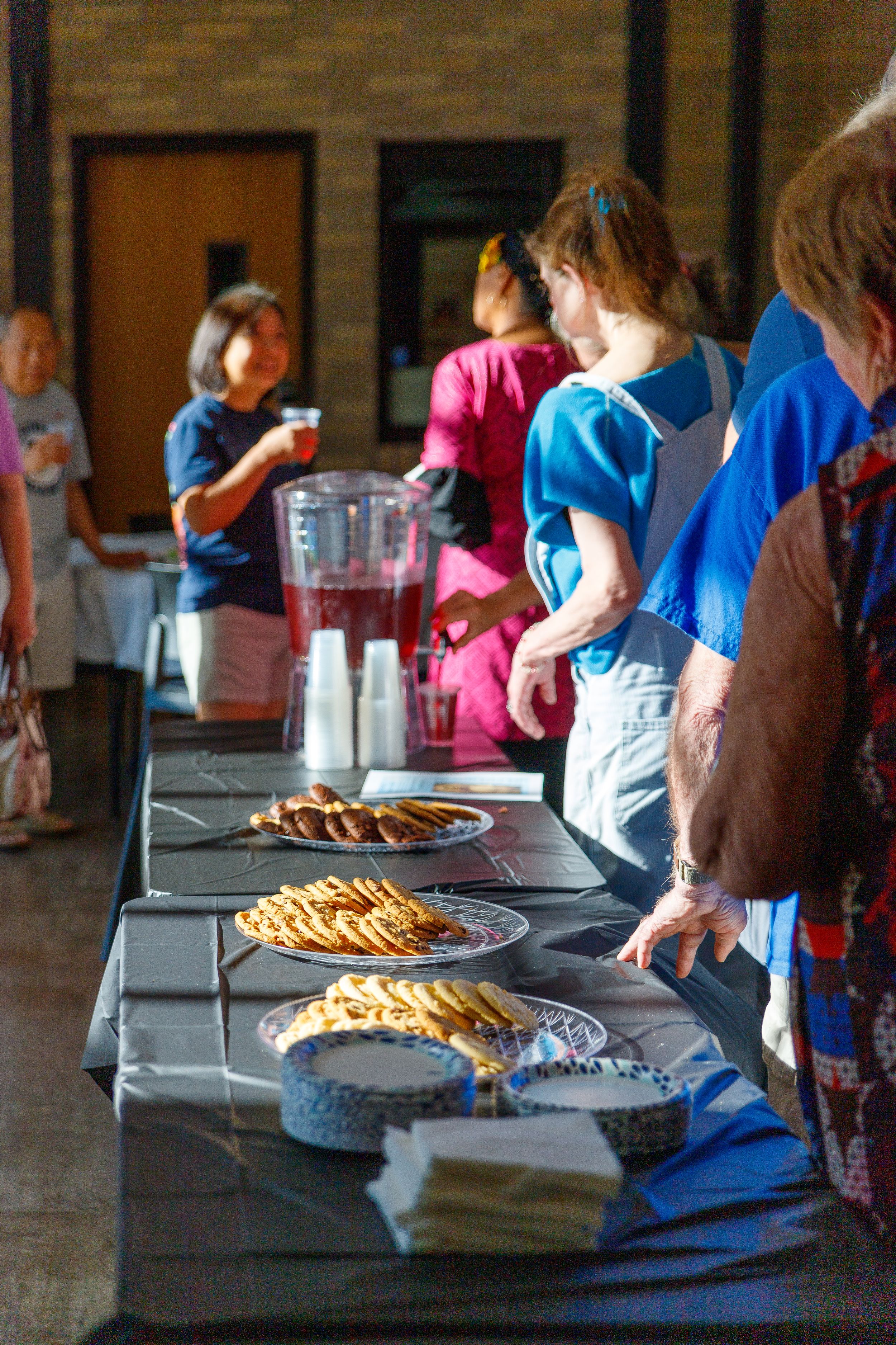 A long table displays multiple homemade pies and beverages at a church gathering.