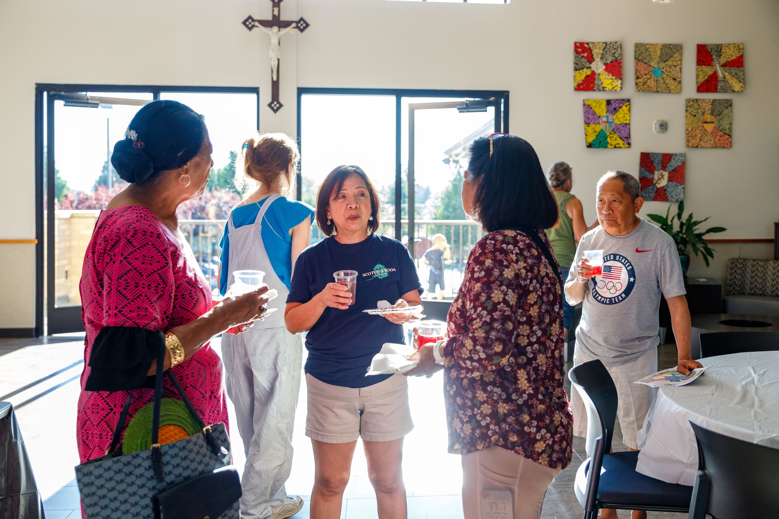 Church members socialize and enjoy refreshments in a bright community room with artwork on walls.