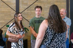 People gathered in casual conversation near a brick wall during a social event.