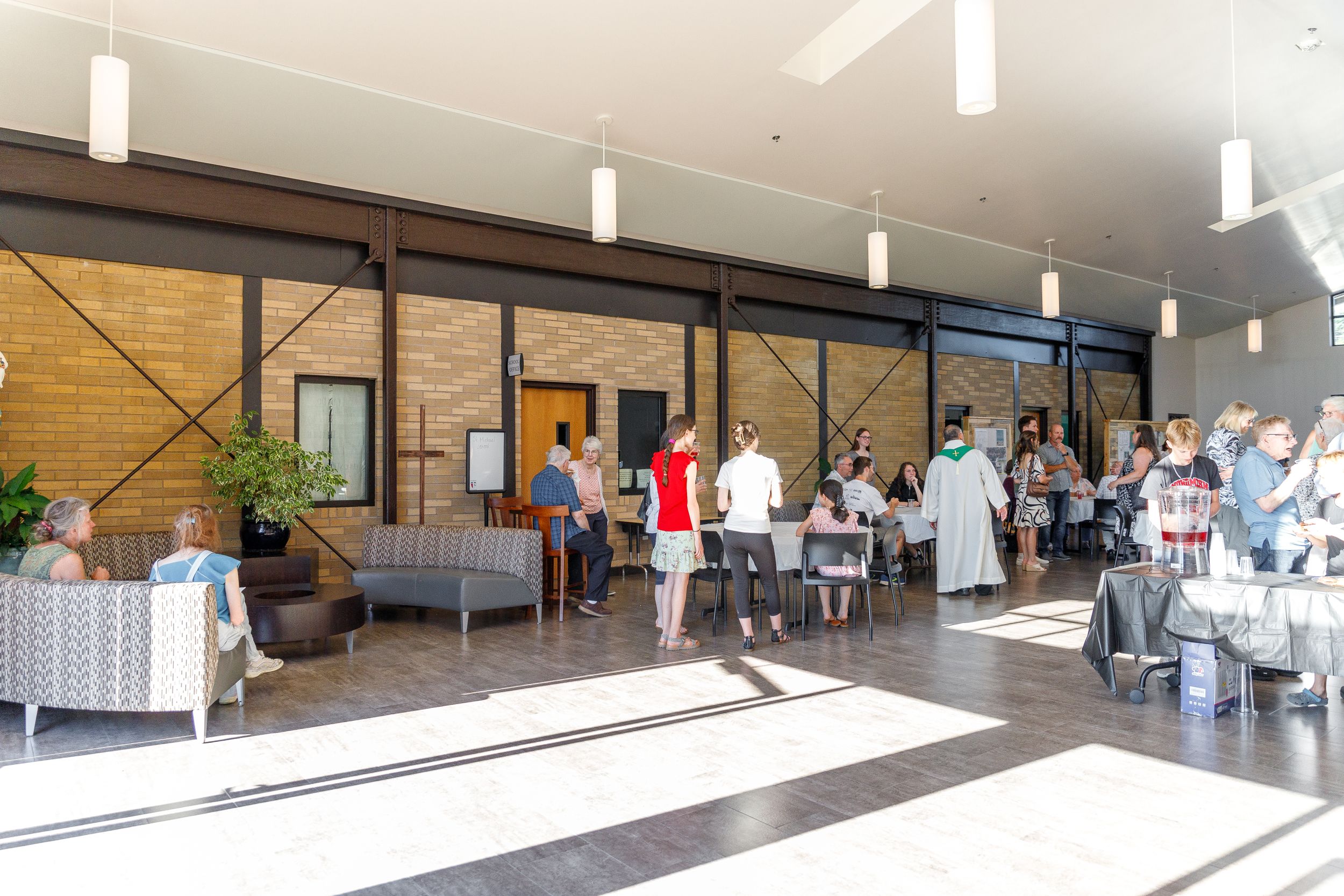 Interior view of a gathering space with tables and people mingling.