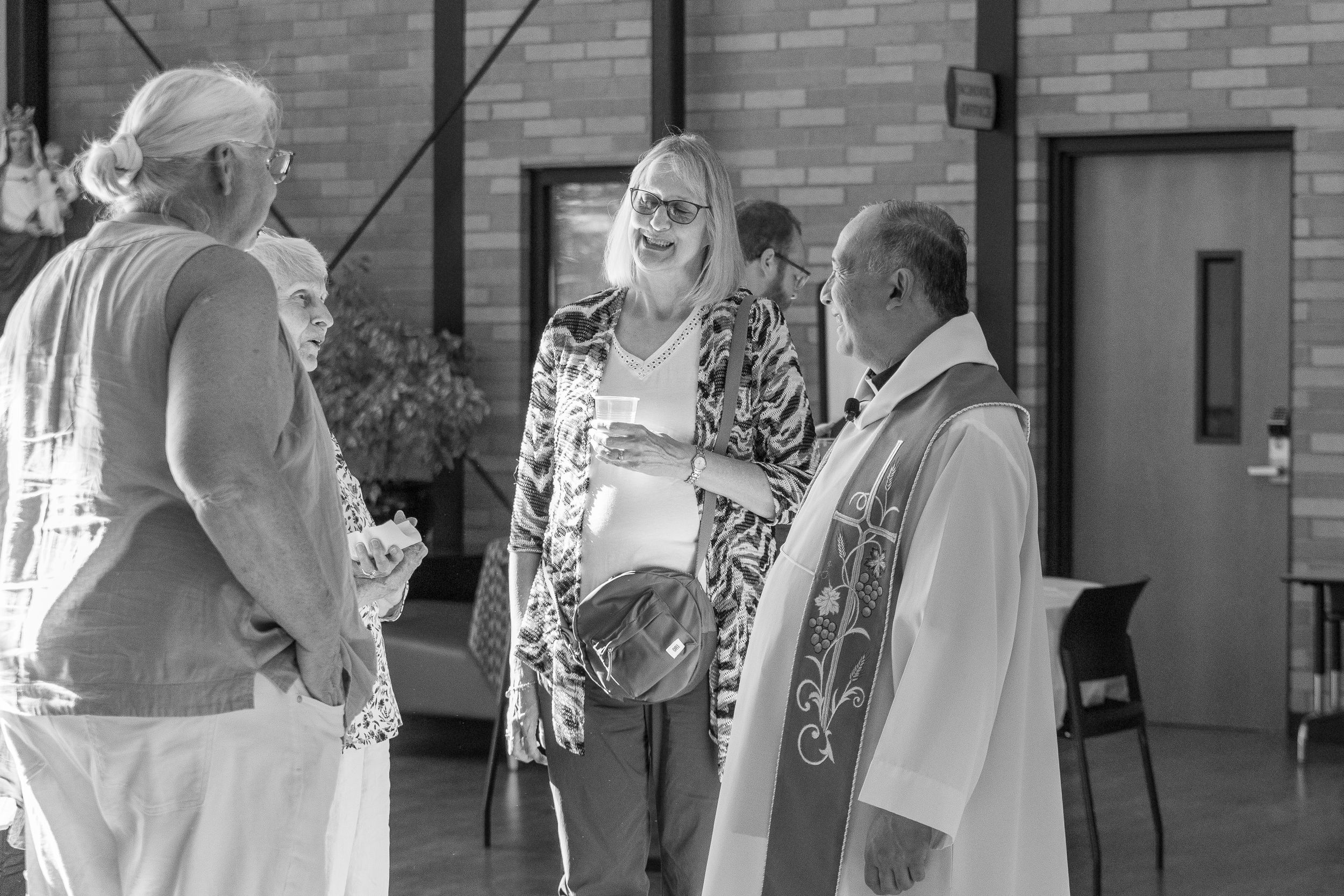 Black and white photo of people conversing in a church gathering space.