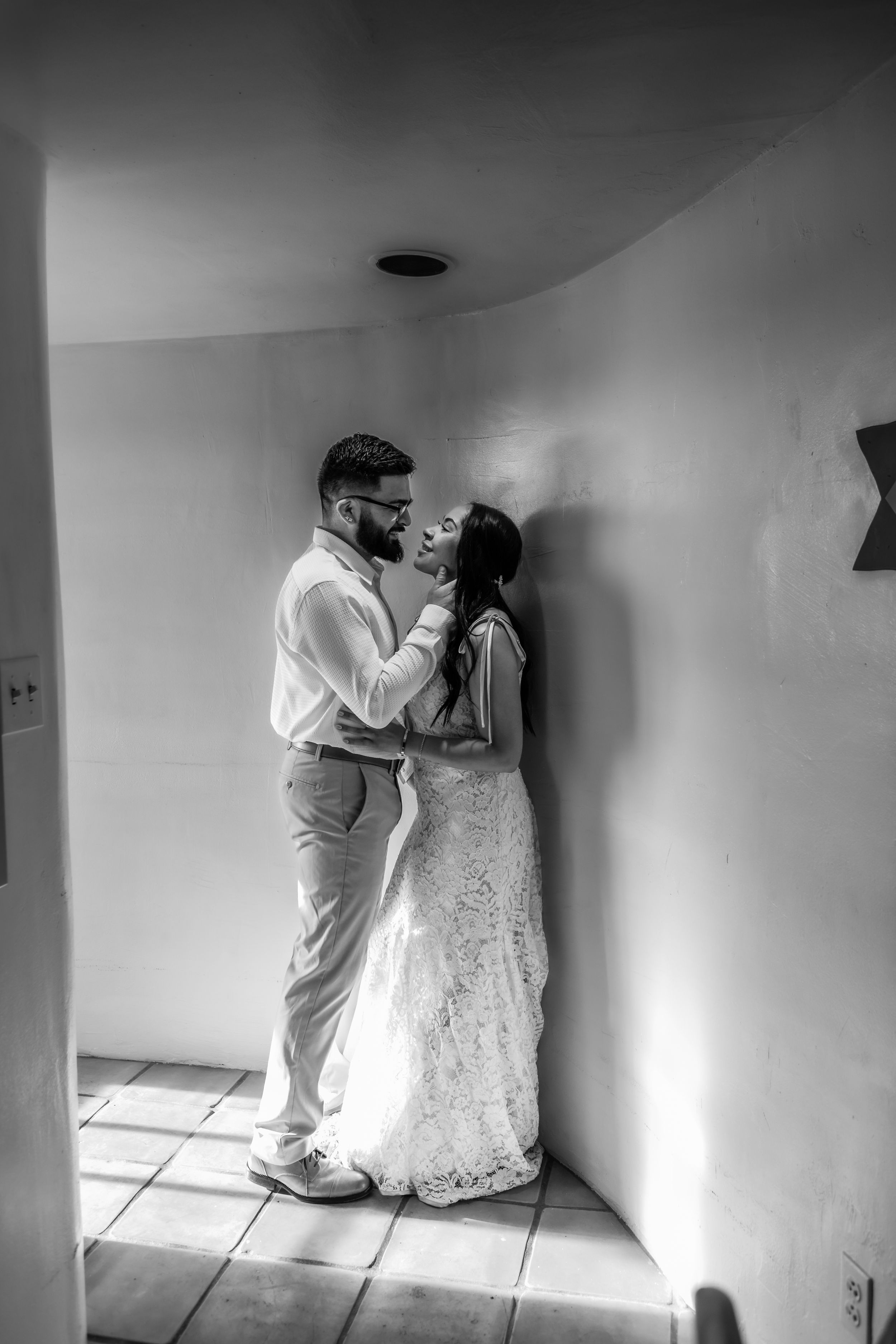 A romantic black and white photograph of a couple in an intimate moment, with the bride wearing a lace gown.