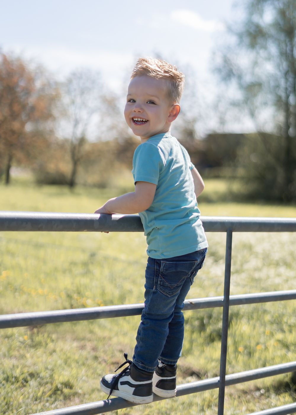 photoshoot ten behoeve van verjaardag. kindje staat op een hek langs een grasveld. gefotografeerd in Druten West Maas en Waal