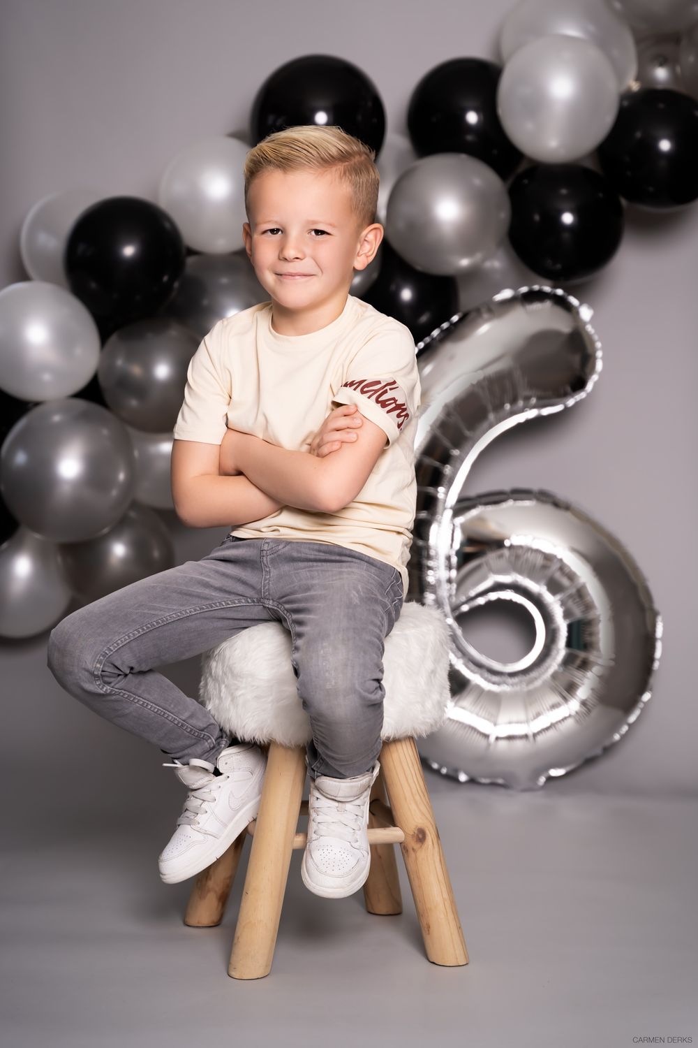 studio photoshoot ten behoeve van verjaardag. kindje zit op kruk met stoere ballonnen op achtergrond.  gefotografeerd in West Maas en Waal.