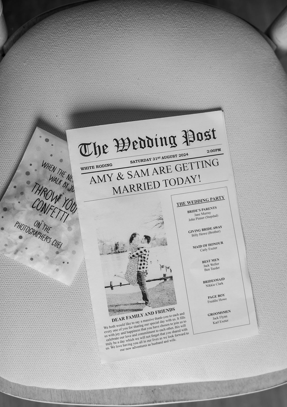 Custom wedding newspaper announcements and invitations laid out on white surface.