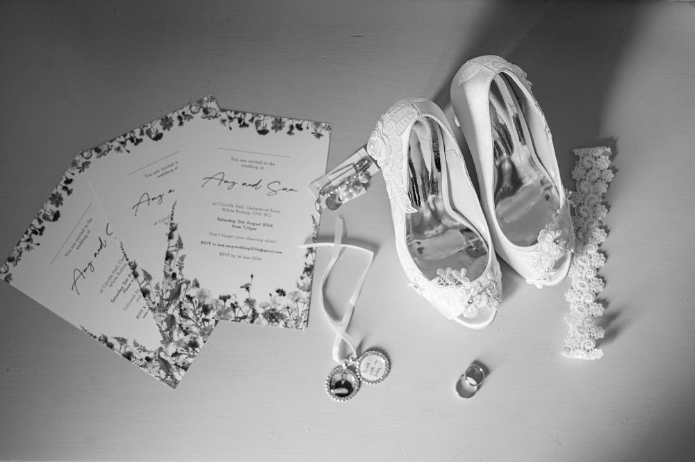 Wedding stationery and bridal shoes arranged artistically in black and white.