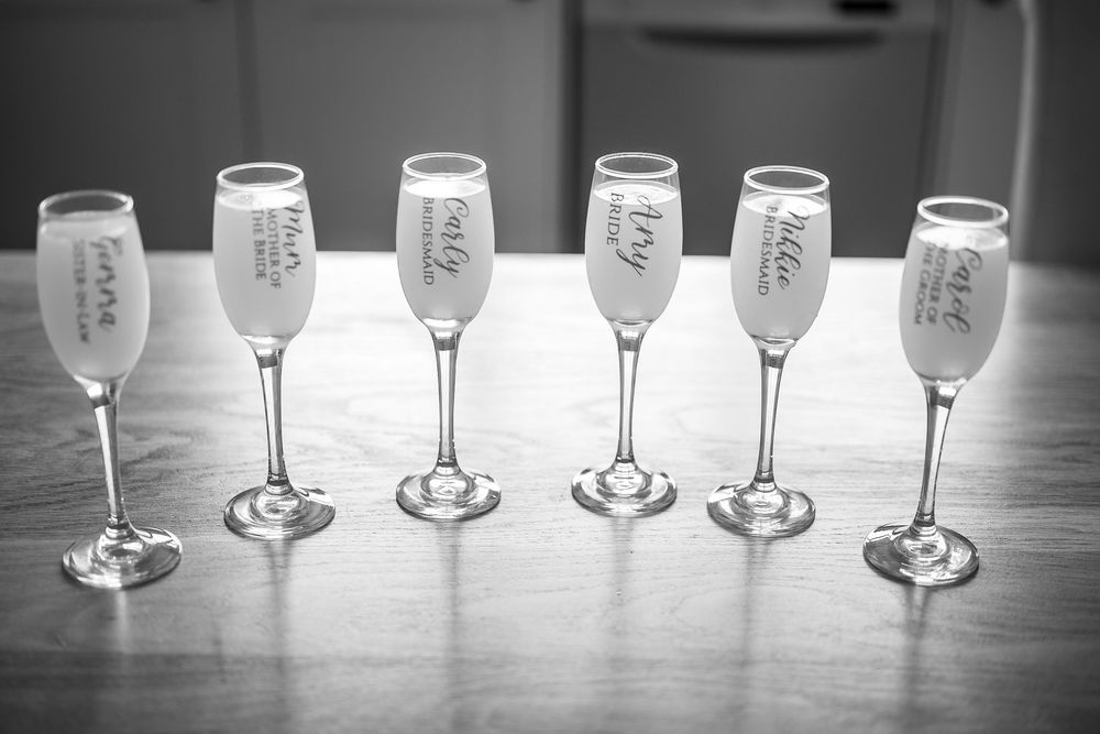 Row of empty champagne glasses lined up on wooden surface in black and white.