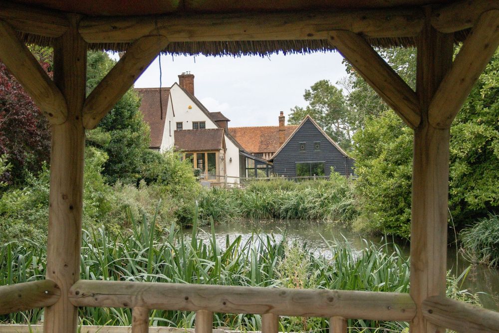 Outdoor wedding venue with wooden pergola and lush garden surroundings.