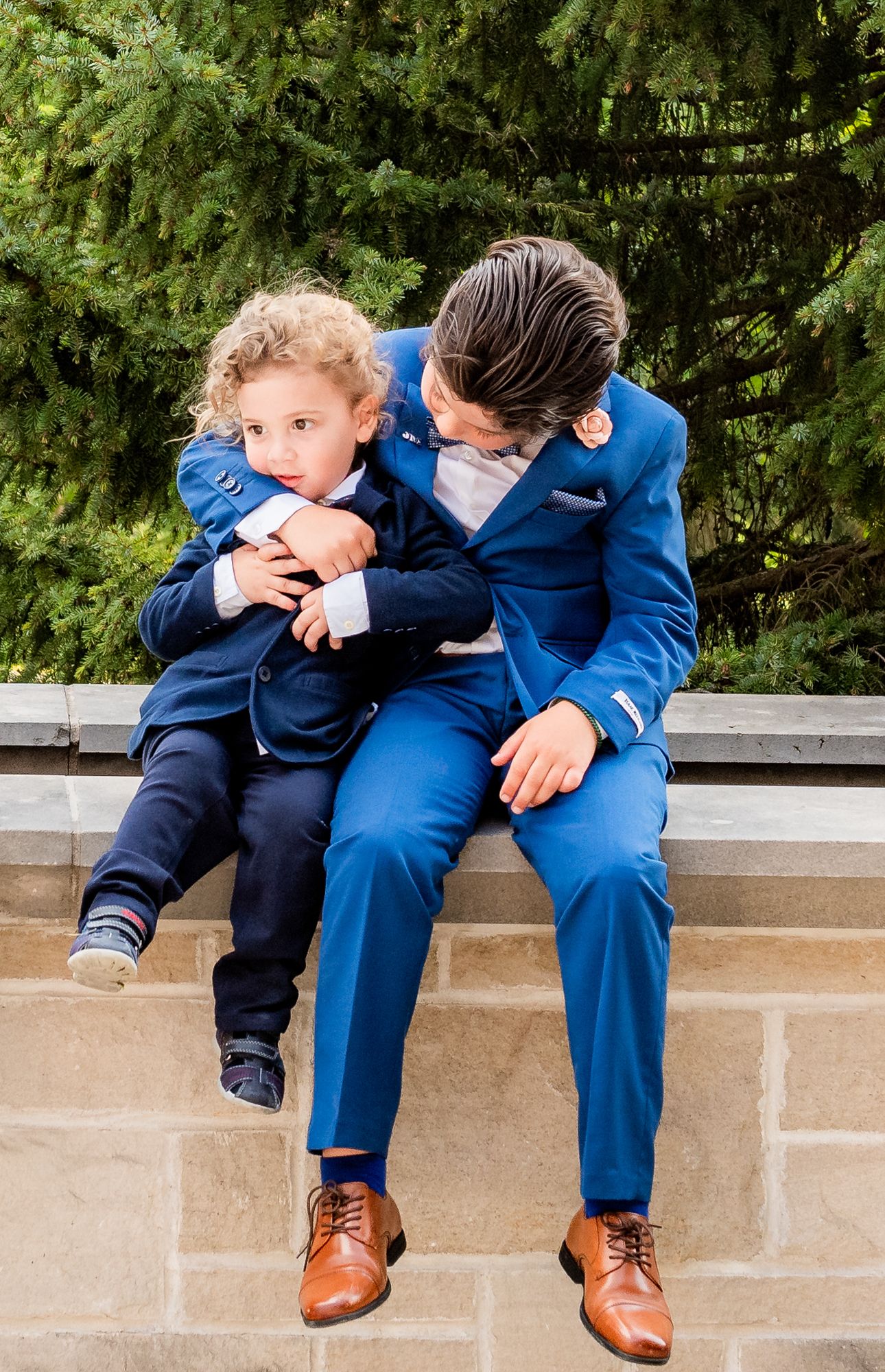 brothers are cuddling during the family photo session at the Firs Communion event at Magna golf club in Newmarket,