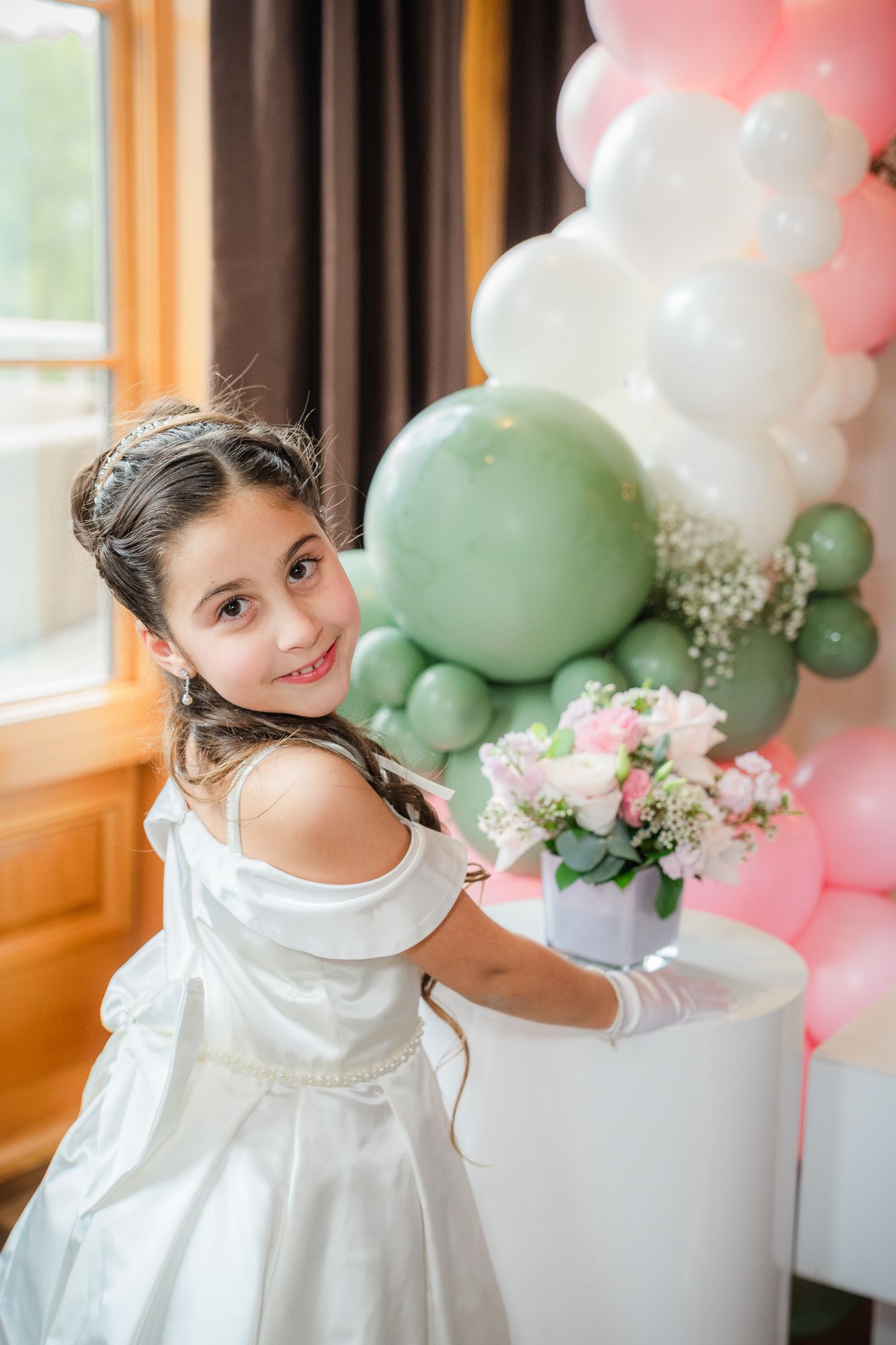 portrait of a girl on her First Communion in a beautiful dress with the flowers and the balloons at Magna golf club