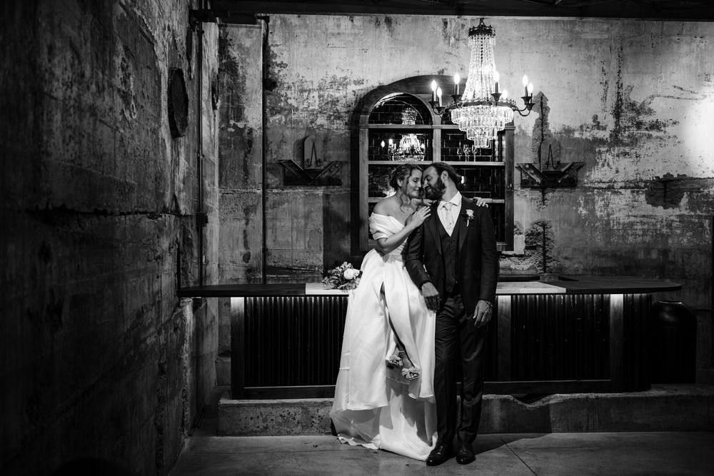 Wedding party dancing and celebrating at a rustic indoor venue during a reception.