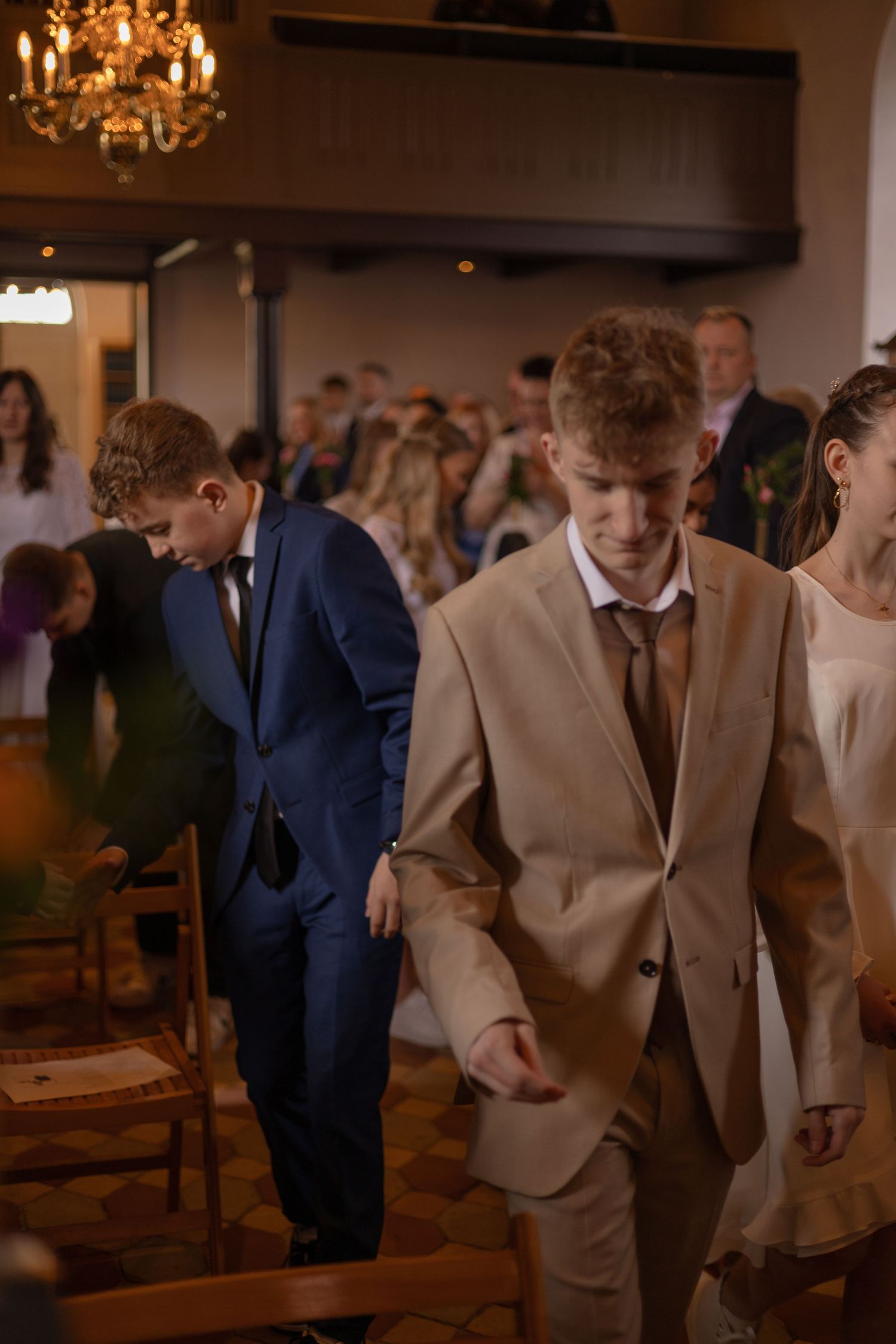 Wedding guests moving through an elegant venue with warm chandelier lighting.