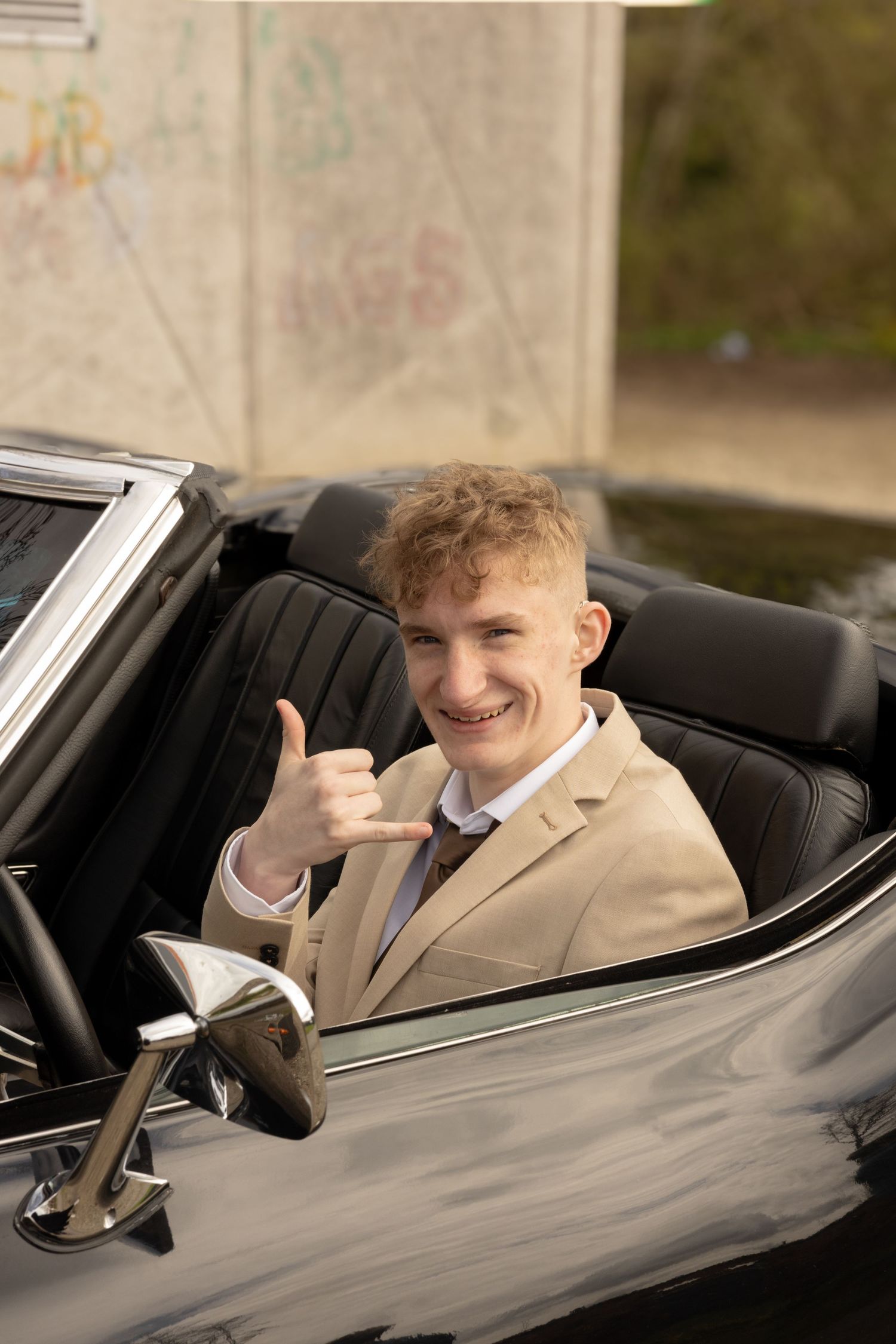 Classic convertible car with driver giving thumbs up gesture.