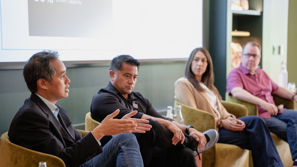 Panel discussion participants engage in conversation while seated in chairs during a professional event.