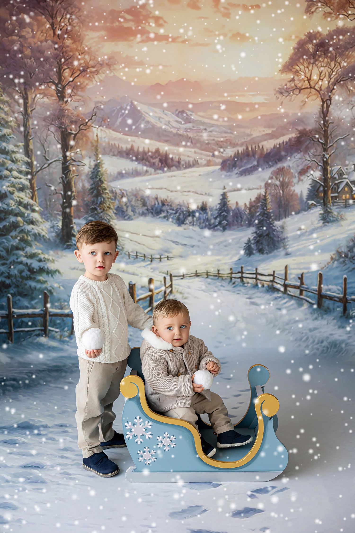Fotografía infantil de hermanos en decorado navideño con nieve y trineo en el estudio de Rosi López Fotografía en Cuenca