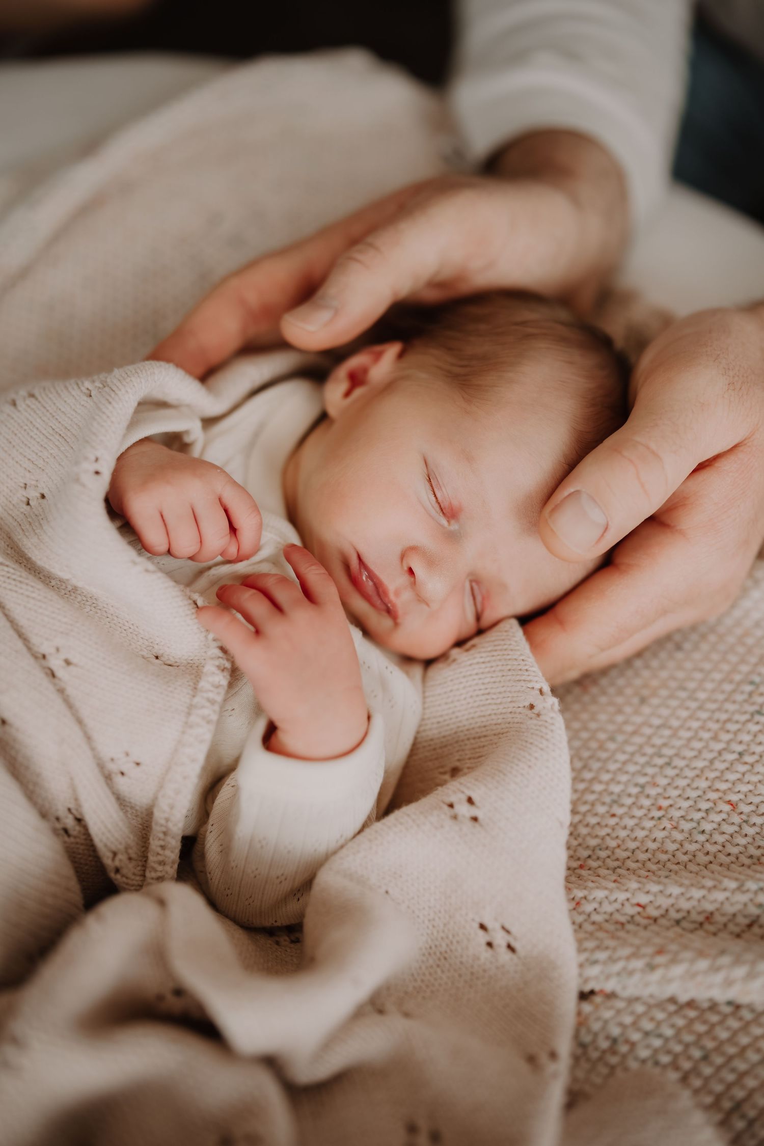 Parents cuddling their newborn baby during a cozy in-home lifestyle photography session in Westport.