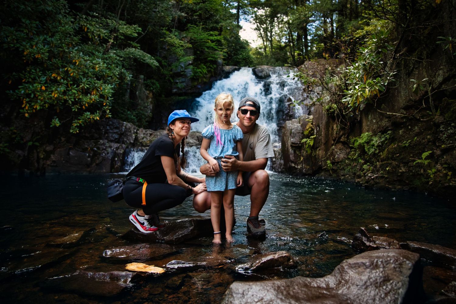 People enjoying a summer day at a natural waterfall swimming hole.