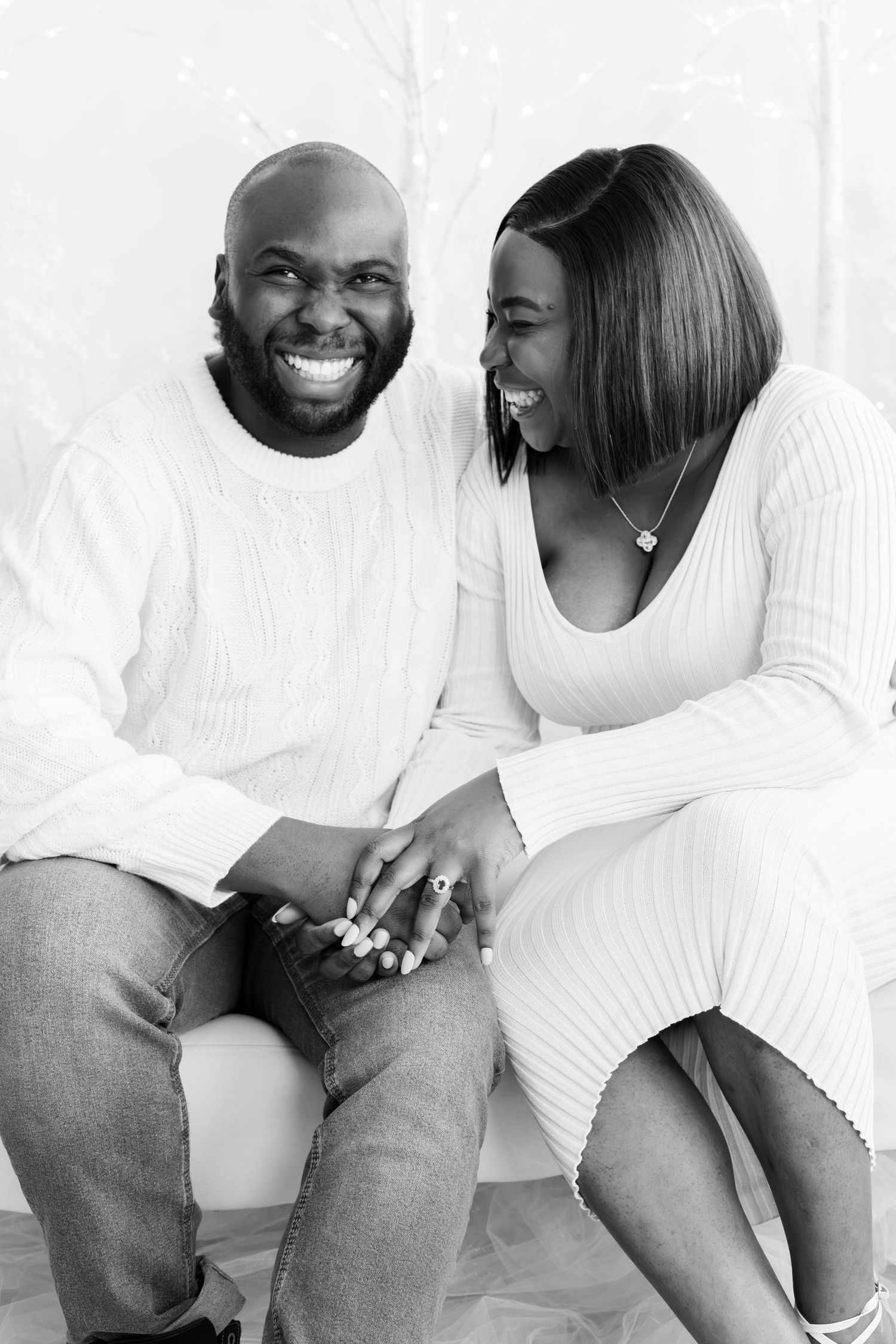 Black and white portrait of couple in white tops sharing genuine laughter.