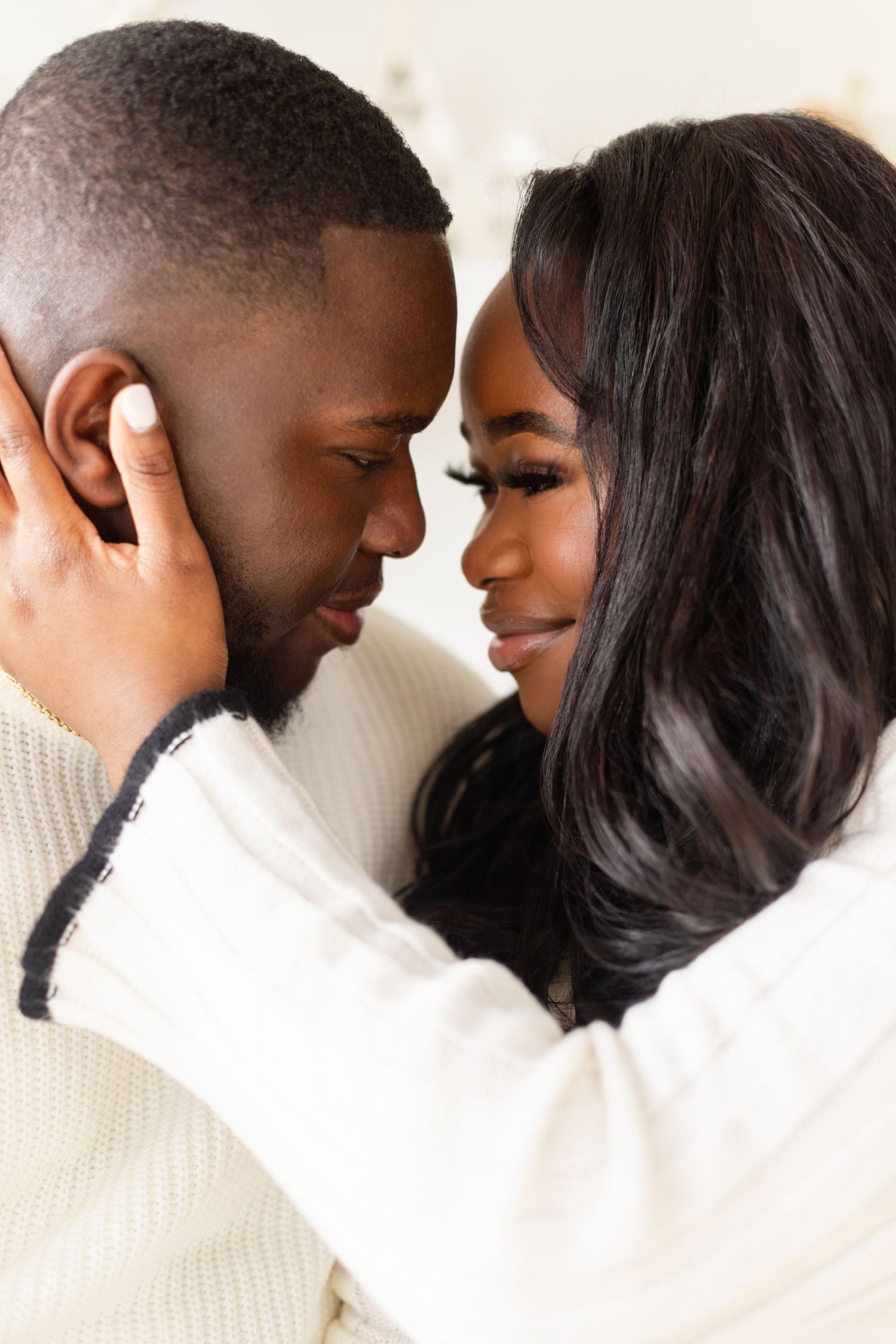 Intimate close-up portrait of couple in cream sweaters sharing tender moment.