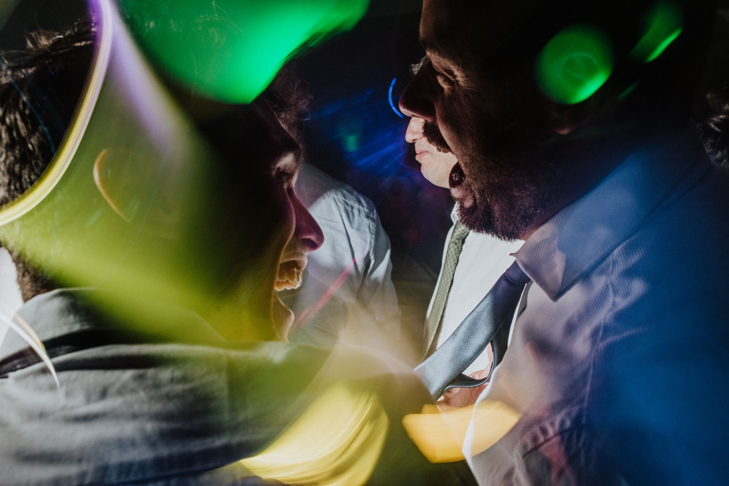 Couple sharing an intimate moment surrounded by colorful green and blue party lights. Fotógrafo de Bodas en Formosa