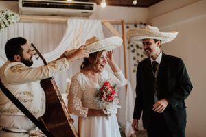 Bride laughs as mariachi musician places a sombrero on her head during a festive wedding ceremony. Fotógrafo de Bodas en Formosa