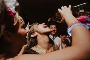Wedding guests laugh and celebrate on a lively dance floor with colorful accessories and bright lights. Fotógrafo de Bodas en Formosa