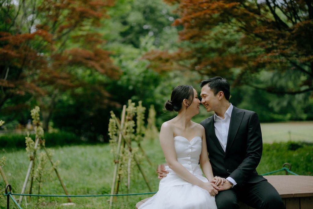 A romantic moment between newlyweds sitting outdoors surrounded by autumn foliage.