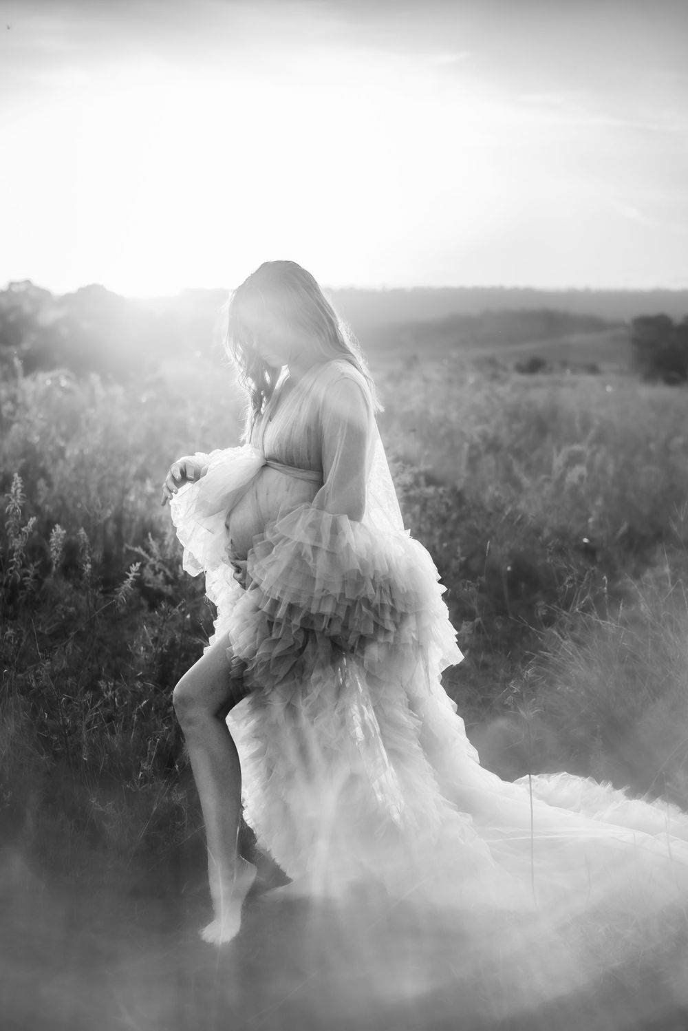 Black and white artistic maternity photo with flowing dress in misty field.