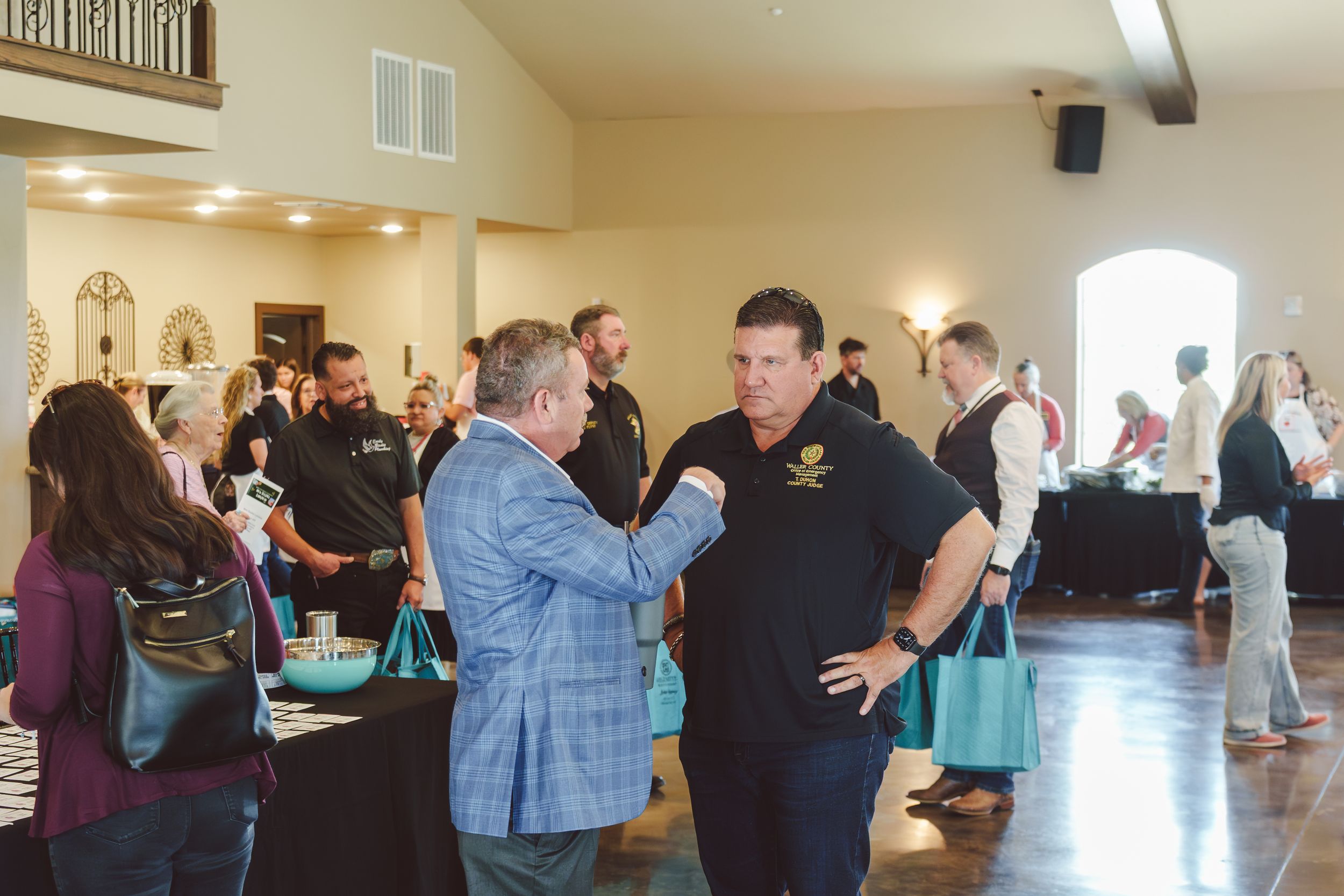 Large group of people gathered in a bright community hall space for a social event or celebration.