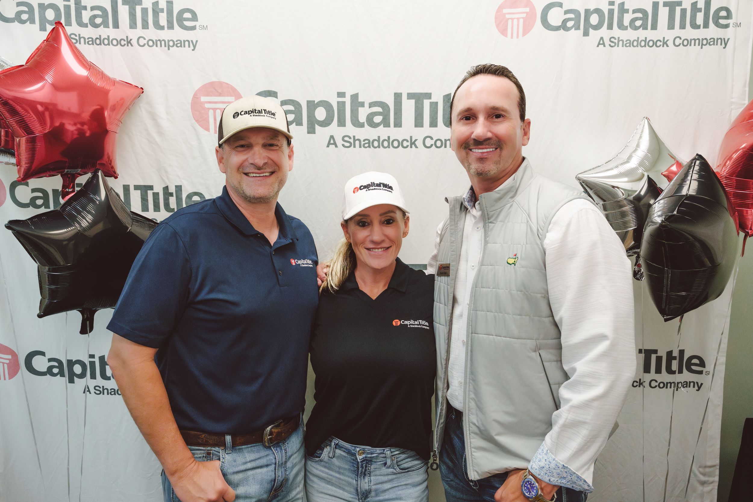 Business professionals gather at a Capital Title event wearing company branded attire and name tags.