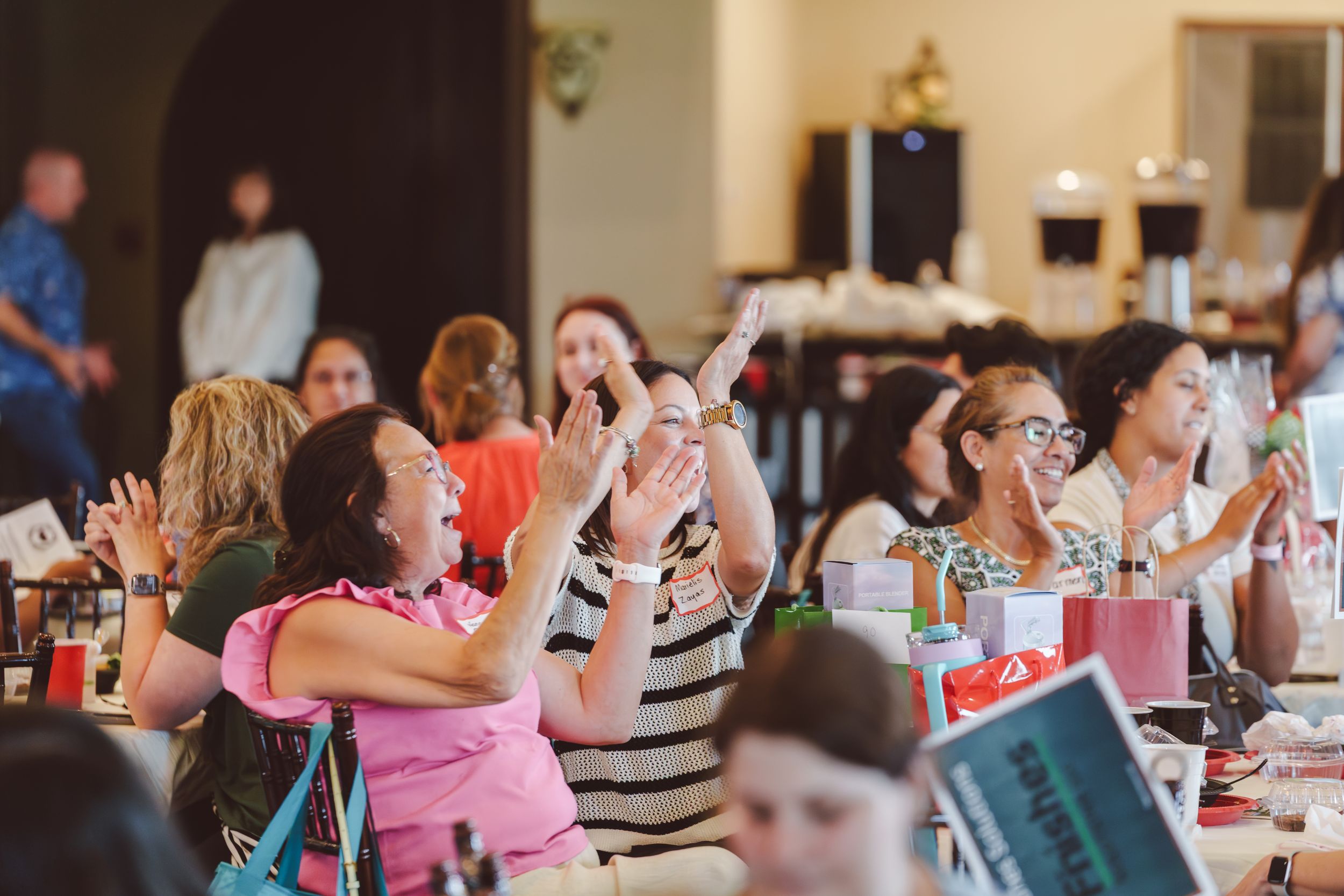 People seated at decorated tables during a social gathering or celebration event.
