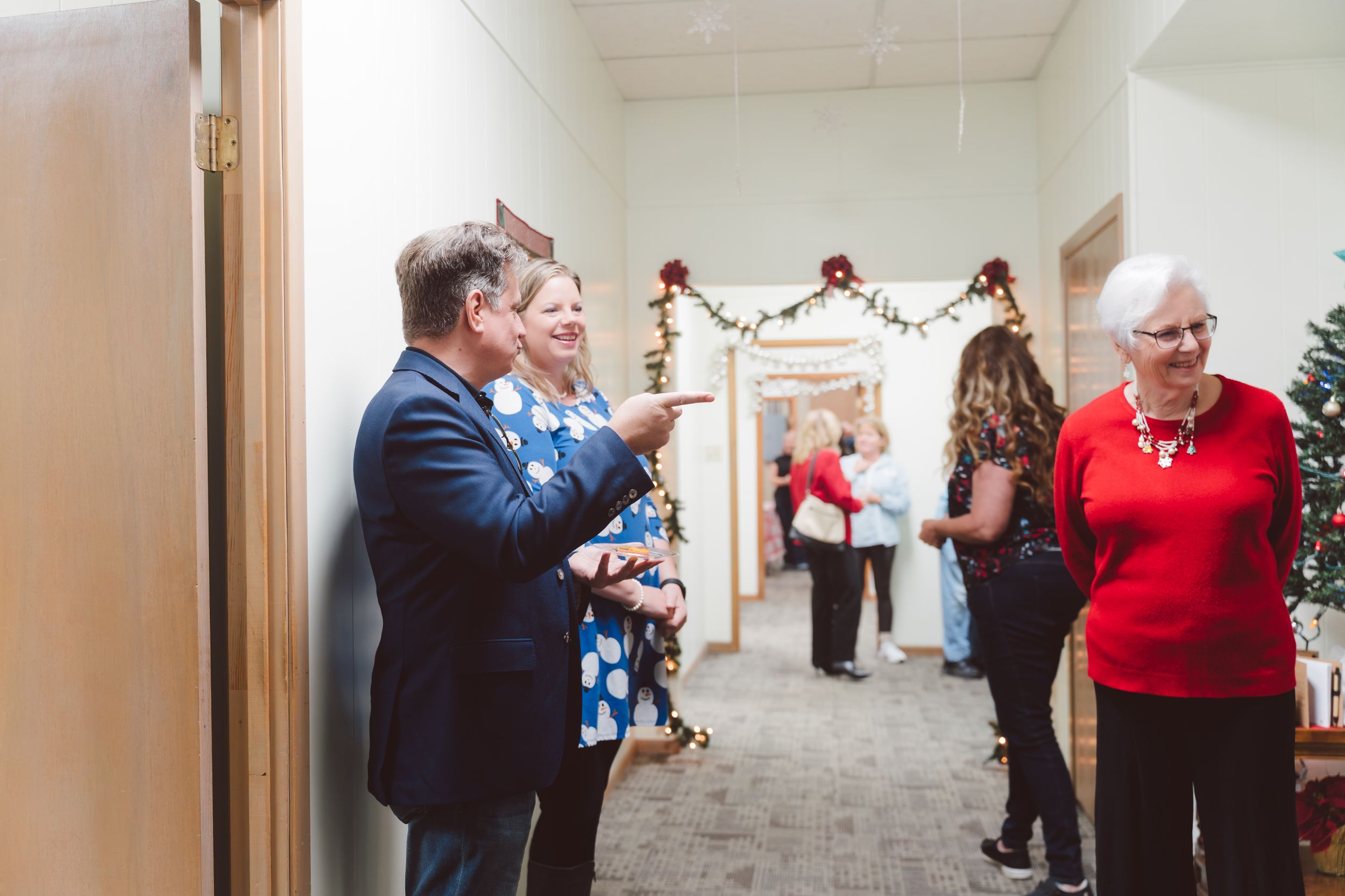 People dancing and celebrating in a hallway decorated for the holiday season.
